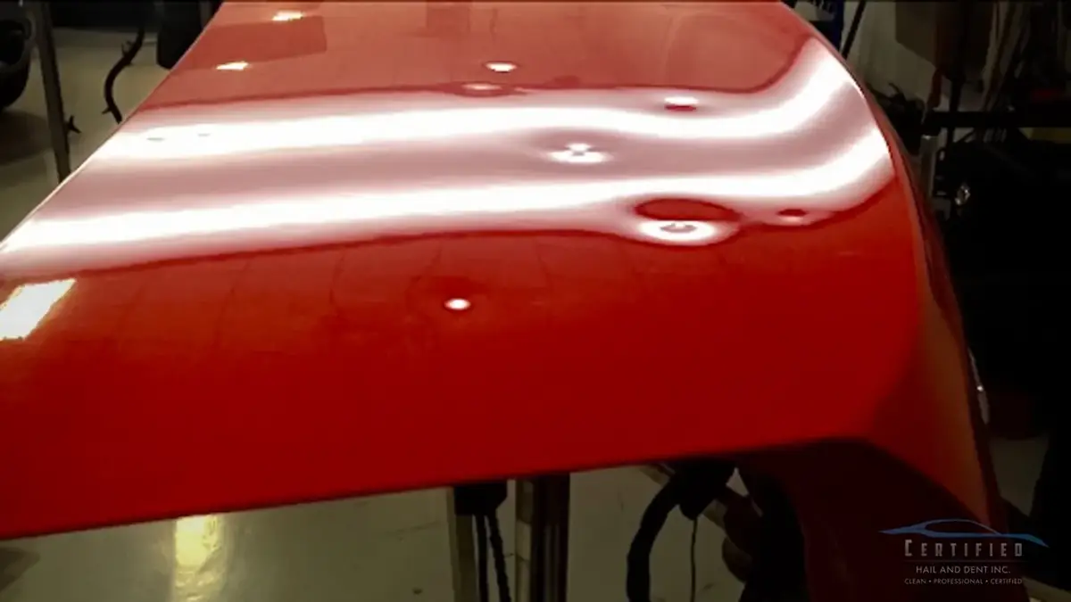 Hood covered in hail dents before repair