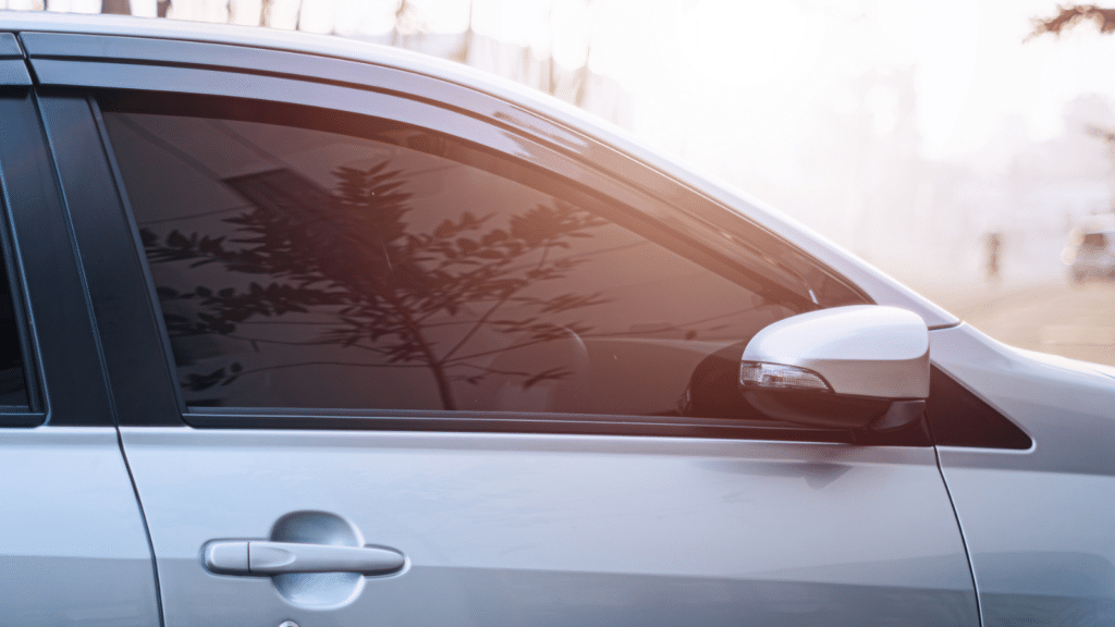 A car with tinted window reflects reddish sunlight and bokeh background