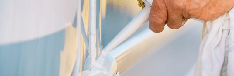 Person hand applying silicone sealant around the edges of caravan