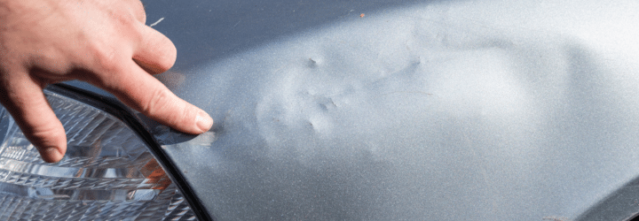 Driver's hand examining the dented car for hidden hail damage