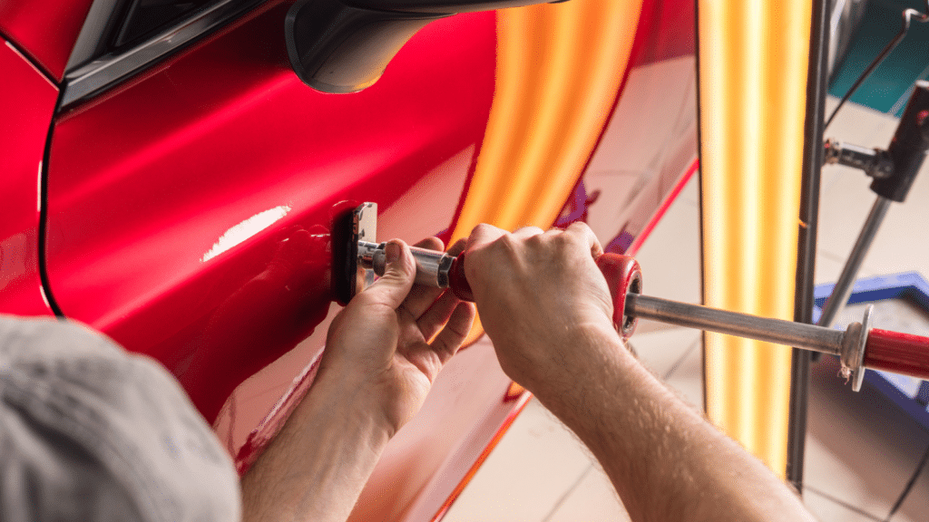 The technician removes dents on the car using the method without painting. PDR